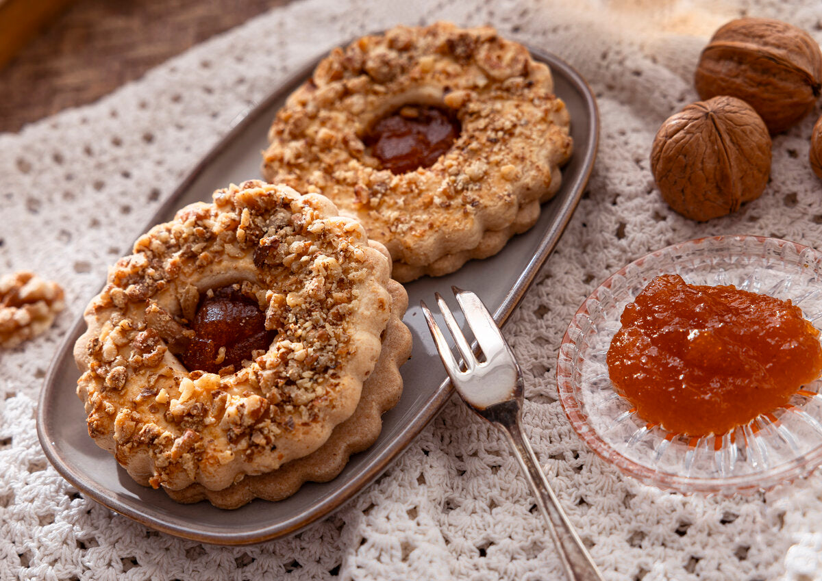 Two Linzer cookies on a plate with an apricot jam filling.