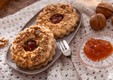 Two Linzer cookies on a plate with an apricot jam filling.