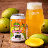 Can and a glass of mango beer with mangos on a wooden background.