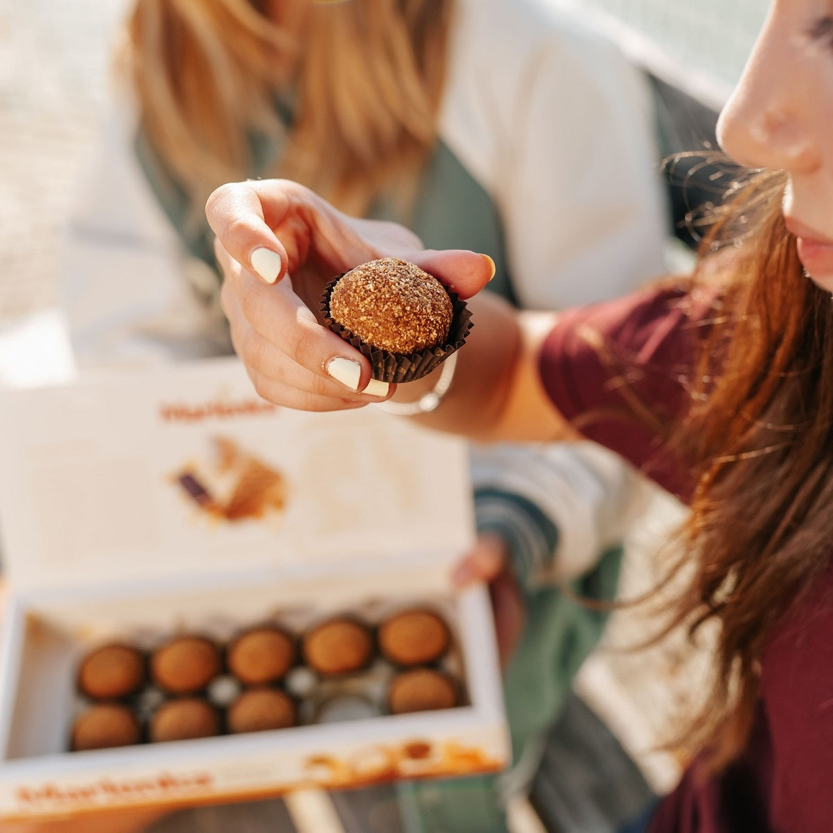 Person holding a Marlenka honey nugget with a box of honey balls in the background.