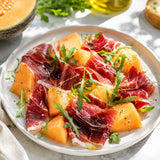 A gourmet starter of honeydew melon, rocket and slices of Mangalitza ham.