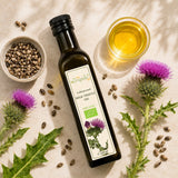Glass container of organic milk thistle oil with milk thistle seeds on a wooden surface.