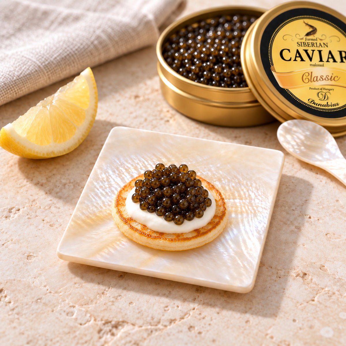 A Mother-of-Pearl Square Dish with a blini topped with caviar and a tin of Danubius Siberian Sturgeon Caviar.