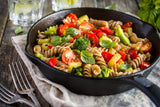 A pan of gluten free oat pasta with roasted vegetables.