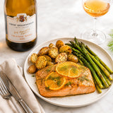 Plated dish of baked salmon with potatoes and asparagus, paired with a bottle of orange wine.