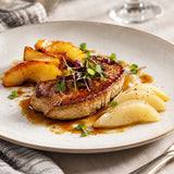 Plate of pan seared foie gras goose liver with caramelised apple, poached pear and micro greens.