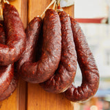 String of dried paraszt kolbász Hungarian sausages hanging on a wooden board.