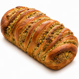 Loaf of braided pistachio babka bread on a white background.