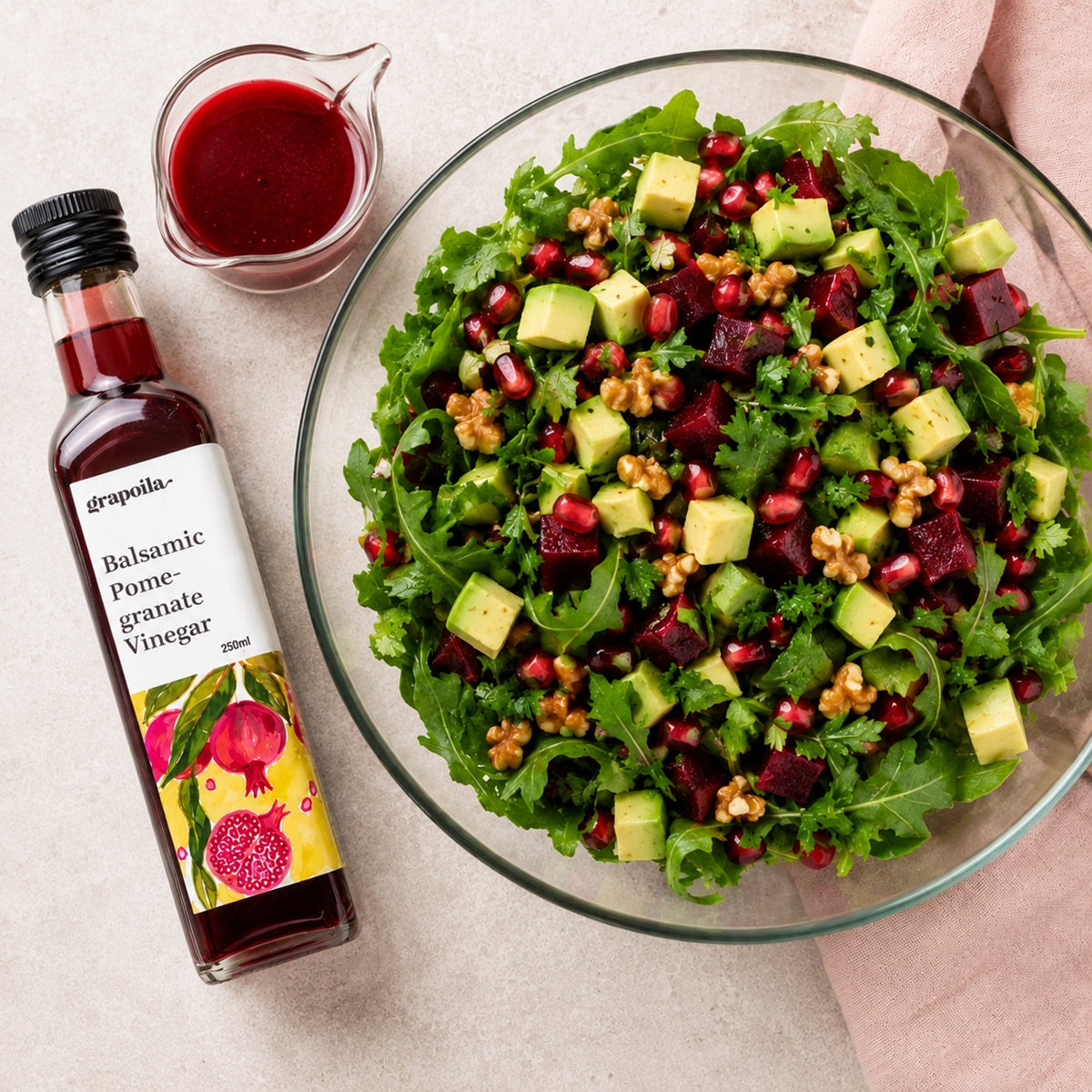 Bowl of salad with a balsamic vinegar dressing and a bottle of pomegranate vinegar on a light background.