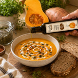 Bowl of butternut squash soup with a drizzle of cream, pumpkin seed oil and a handful of seeds.