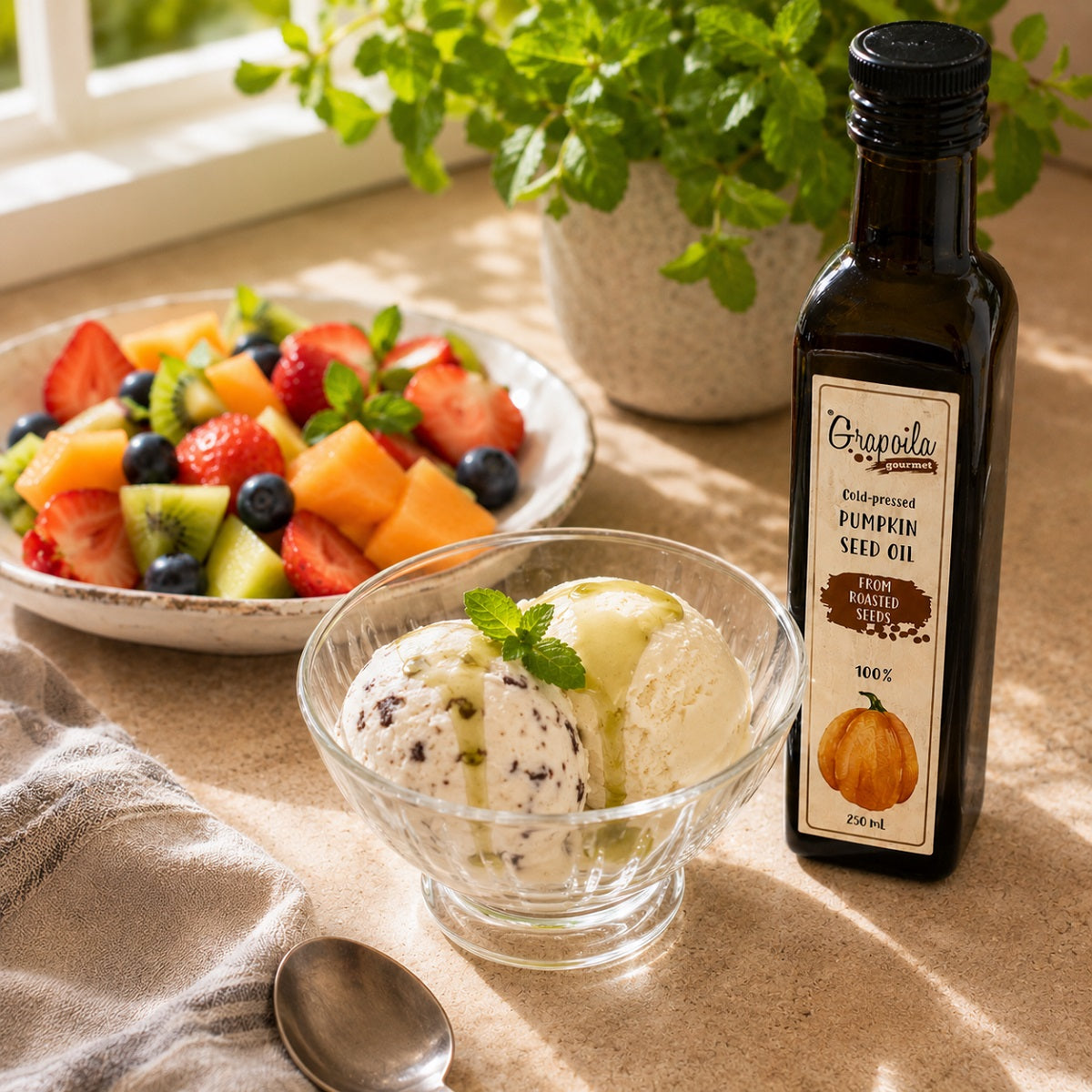 Bowl of ice cream with a drizzle of pumpkin seed oil and a plate of fresh fruit in the background.