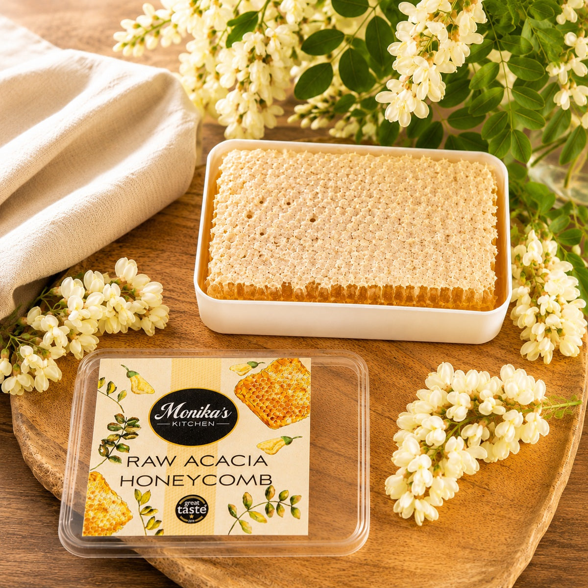 A piece of pure and natural raw honeycomb in a tin on a wooden surface with acacia flowers around.
