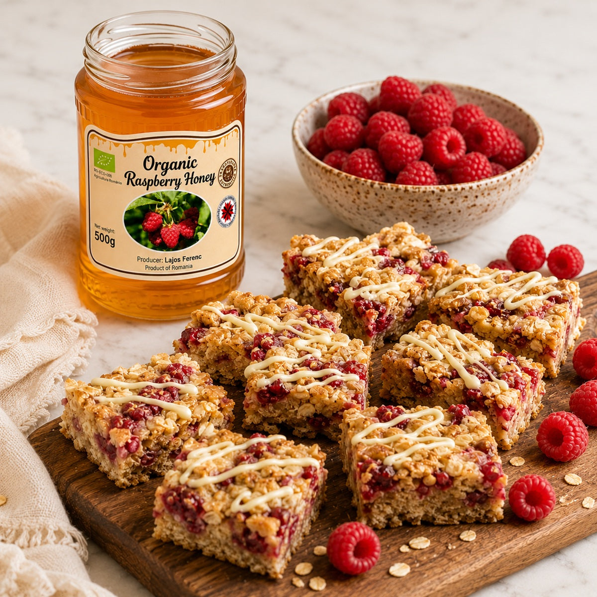Raspberry honey flapjacks on a wooden board with a jar of organic raspberry honey and a bowl of fruit.