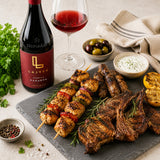 A bottle of Lajver Kadarka red wine with a plate of grilled meats including lamb, beef, sausage and chicken shaslik.
