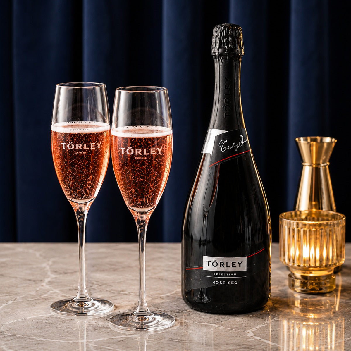 Two glasses of Törley Rosé sparkling wine with a bottle of the same wine on a marble surface with a dark background.
