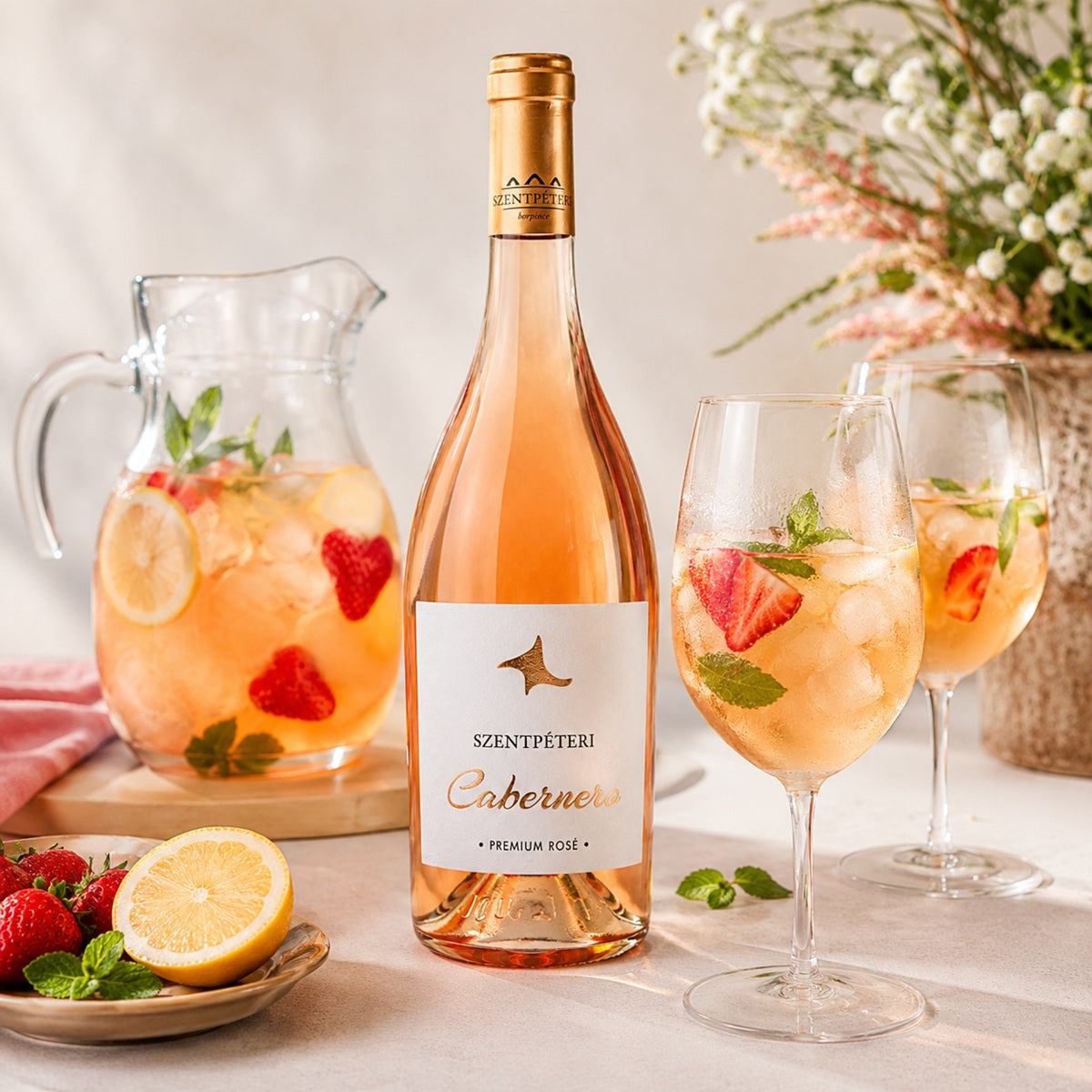 A bottle of Szentpeteri rose wine with glasses and a fruit cocktail made with lemonade on a table.