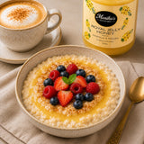 Bowl of oatmeal with fruits, drizzled with honey and a jar of royal jelly honey in the background.