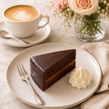Slice of Sacher torte cake with a cup of coffee on a light background.