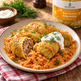 A dish of stuffed cabbage rolls on shredded sauerkraut, garnished with dill and sour cream, with a jar of Hungarian sauerkraut.