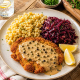 A plated meal of breaded schnitzel topped with peppercorn sauce, served with spaetzle noodles and red cabbage.