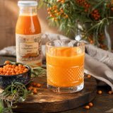 Glass of sea buckthorn juice with a bowl of sea buckthorn berries and a bottle of sea buckthorn juice.
