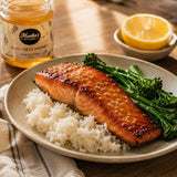 Plate of honey-glazed salmon with rice and broccolini, Monika's Smoked Honey jar in the background