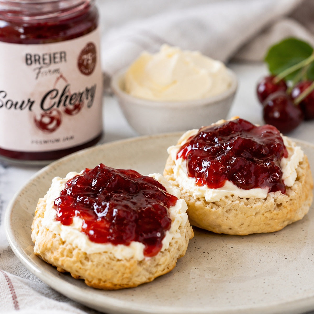 Scones with clotted cream and sour cherry jam on top.