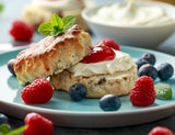 Healthy strawberry jam on a scone with clotted cream and fresh berries.