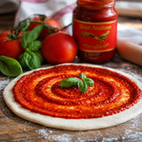 Pizza sauce made with tomato concentrate spread on pizza dough and topped with basil leaves.