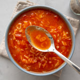 A bowl of tomato soup made with tomato concentrate and served with alphabet pasta.
