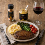 Plate with steak, mashed potatoes, and vegetables, seasoned with truffle powder, served with a glass of red wine.