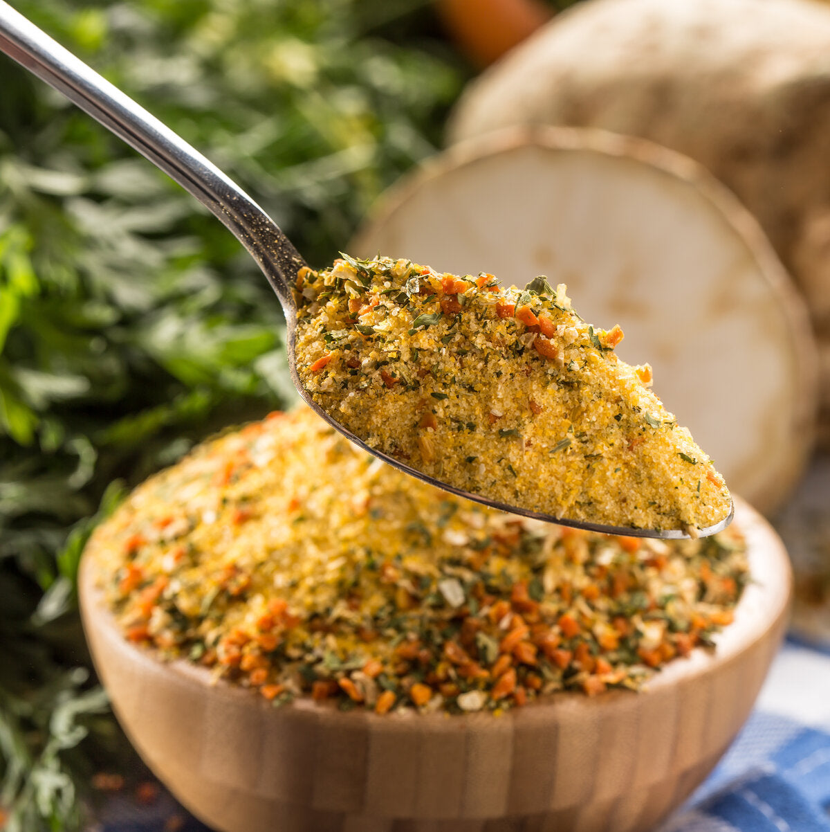 Spoonful of Vegeta seasoning blend made from vegetables, herbs and spices, over a bowl.