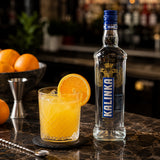 Classic screwdriver cocktail with vodka and orange juice, served with a slice of orange in a bar setting.