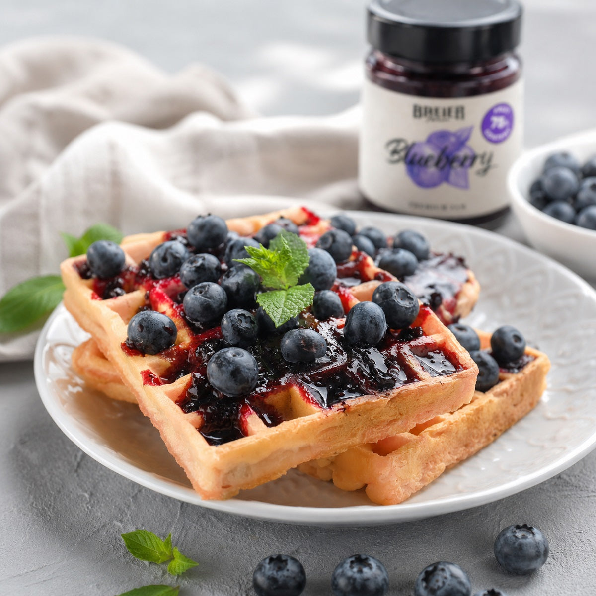 Waffles with low-sugar blueberry jam and pieces of fresh fruit on top.