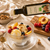 Bottle of walnut oil being gently drizzled over a bowl of ice cream with fruit.