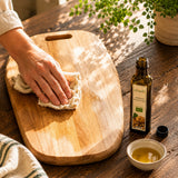 Person polishing a wooden chopping board with a cloth soaked in walnut oil.