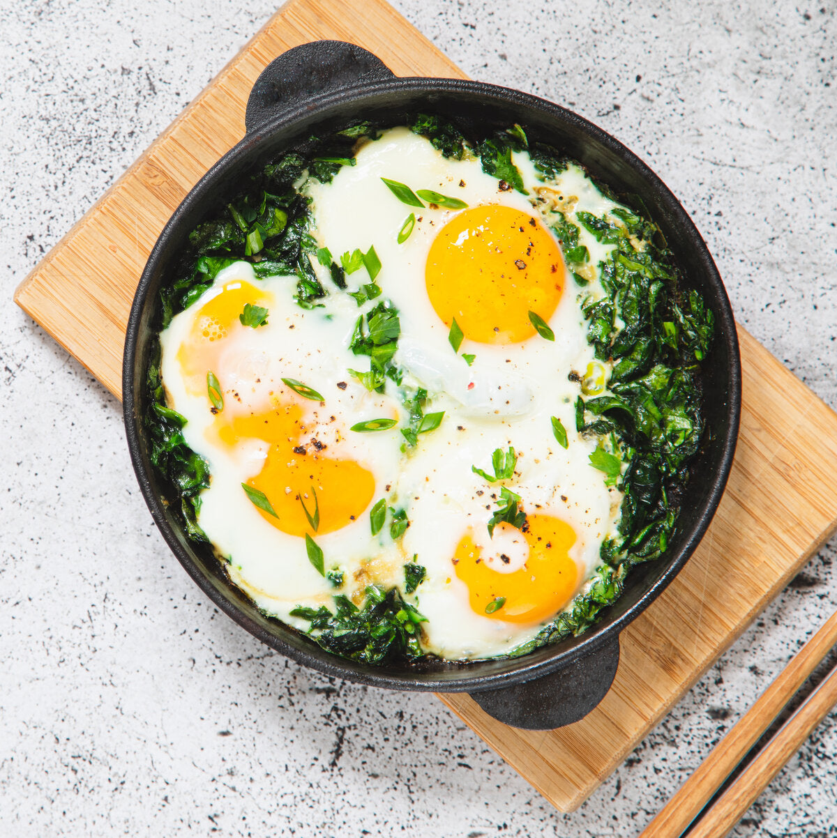 Fried eggs in a skillet sprinkled with wild garlic.