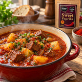 Hungarian sweet paprika pouch behind a pot of traditional goulash with paprika powder.
