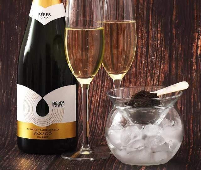 A caviar dish with fresh caviar on ice, paired with a glass of Champagne.