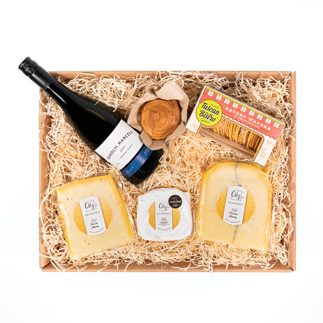 A luxury cheese and wine hamper with a selection of cheese, crackers and a bottle of red wine.