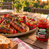 A plate of BBQ sausage, onions and grilled peppers with a jar of Haragos Pista, an extra-hot pepper paste.