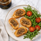 Black truffle carpaccio slices in oil, served on toasted bruschetta bread with rocket leaves and tomato.